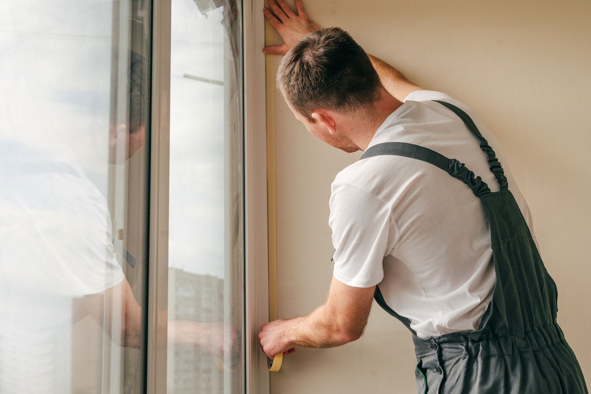 Young man applying mounting tape before sealing a window